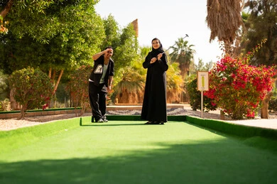 زوجان سعوديان يلعبان ميني غولف في حديقة خارجية
