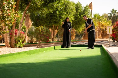 زوجان سعوديان يلعبان ميني غولف في منتزه خارجي