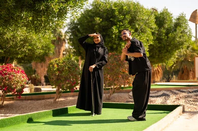 زوجان سعوديان يلعبان الميني غولف في حديقة خارجية