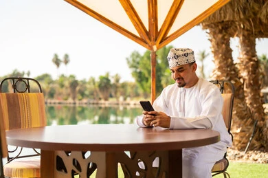 Omani Man Using Smartphone at Outdoor Resort