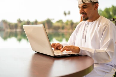رجل عماني يستخدم الحاسوب المحمول بزي تقليدي
