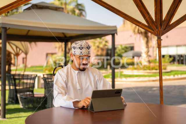 رجل عماني يستخدم جهاز لوحي بالملابس التقليدية