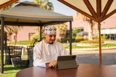رجل عماني يستخدم جهاز لوحي بالملابس التقليدية
