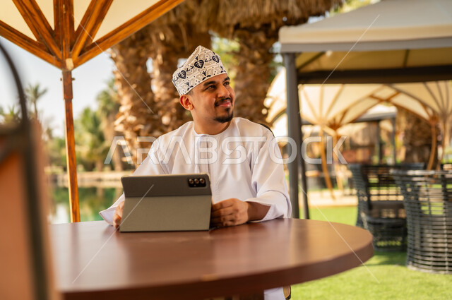 Omani Man with Tablet at Outdoor Resort Setting