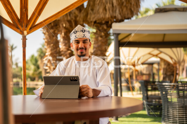 Omani Man with Tablet at Outdoor Tropical Resort