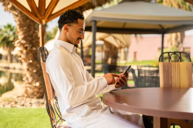 Saudi Man in Traditional Thobe Using Smartphone