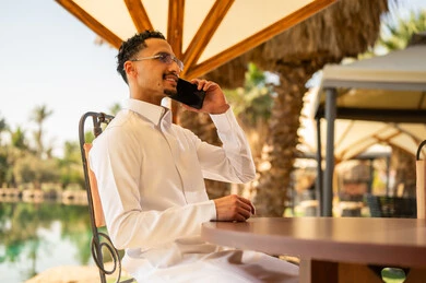 رجل سعودي بالثوب يتحدث بالهاتف في مكان خارجي