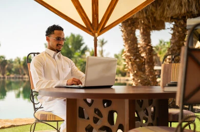 رجل سعودي بالثوب التقليدي يعمل على المحمول في الخارج