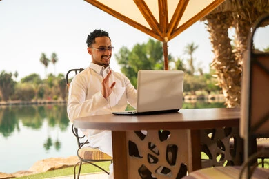 رجل سعودي يستخدم المحمول لمكالمة فيديو بجانب البحيرة