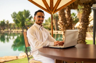 رجل سعودي يستخدم الكمبيوتر المحمول في منتجع خارجي