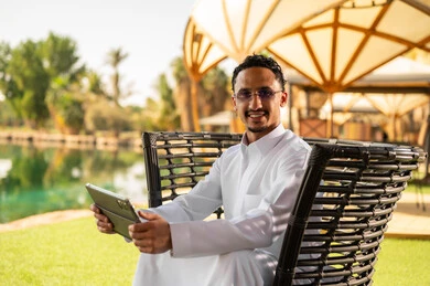 رجل سعودي يرتدي الثوب ويستخدم جهازاً لوحياً