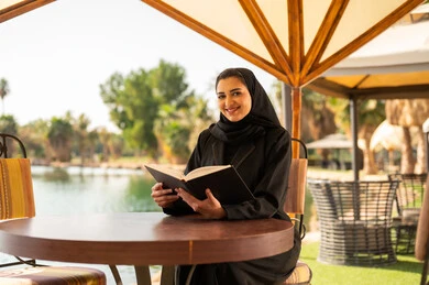 امرأة إماراتية تقرأ كتاباً في جلسة خارجية