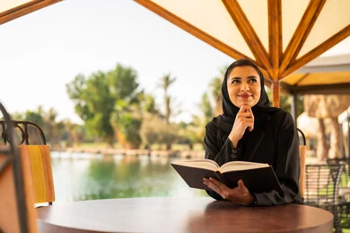 امرأة سعودية بالعباية تقرأ كتاب في الخارج