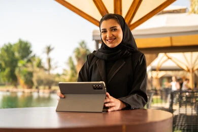 سيدة أعمال عربية مع جهاز لوحي في مقهى خارجي