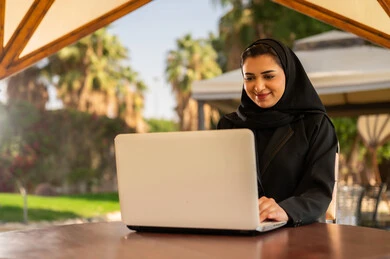 امرأة سعودية تعمل على الكمبيوتر المحمول في حديقة