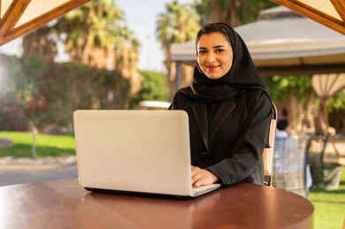 Emirati Businesswoman Working on Laptop at Outdoor Cafe