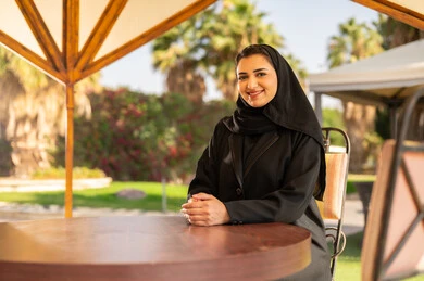 امرأة سعودية بالعباءة السوداء تجلس في حديقة خارجية