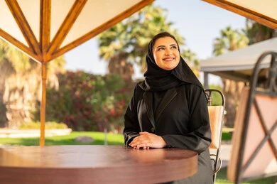 امرأة سعودية بالعباءة التقليدية تجلس في الحديقة