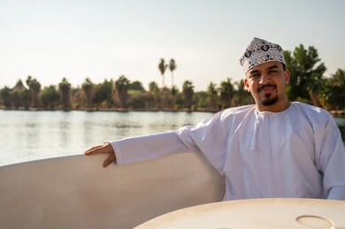 رجل عماني بالزي التقليدي بجانب بحيرة طبيعية