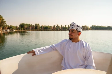 رجل عماني بالزي التقليدي في قارب بالبحيرة