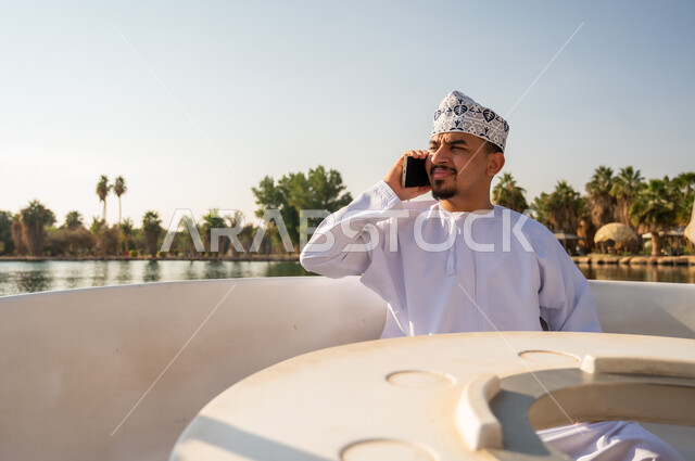 Omani Man in Traditional Dress on Boat Using Smartphone