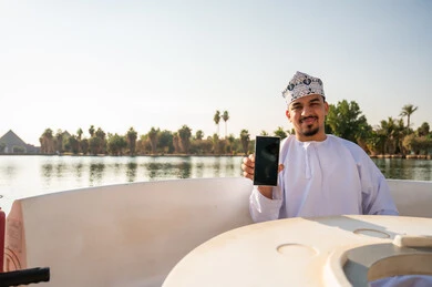 Omani Man Holding Smartphone on Lake Boat Trip