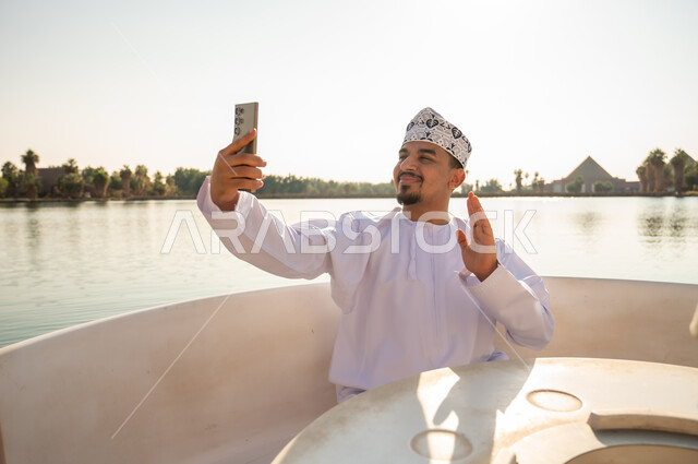رجل عماني بالزي التقليدي يلتقط سيلفي على قارب