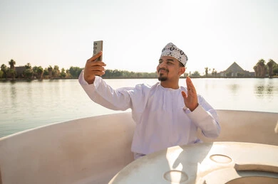 رجل عماني بالزي التقليدي يلتقط سيلفي على قارب