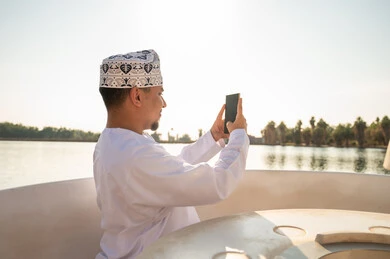 رجل عماني بالزي التقليدي يستخدم الهاتف الذكي