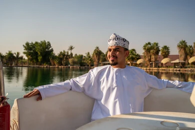رجل عماني بالزي التقليدي على متن قارب وقت الغروب