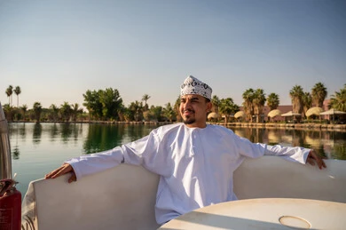 رجل عماني بالزي التقليدي على قارب في منتجع