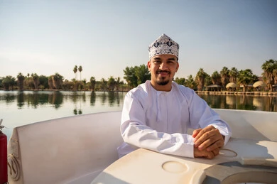 رجل عُماني بالزي التقليدي في بحيرة الحديقة