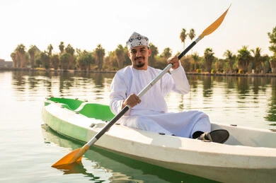 رجل عماني يجدف في قارب كاياك بالزي التقليدي