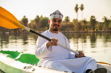 Omani Man in Traditional Dress Kayaking on Lake