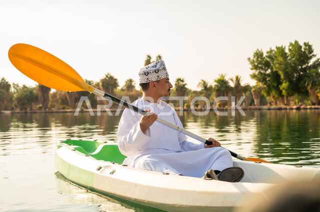Omani Man in Traditional Dress Kayaking on Lake