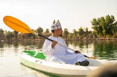 رجل عماني باللباس التقليدي يجدف في الكاياك