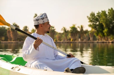 رجل عماني يمارس التجديف بالكاياك بالملابس التقليدية