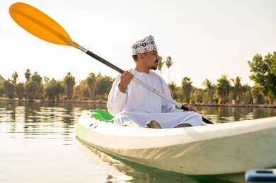 Omani Man in Traditional Dress Kayaking on Lake