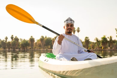 رجل عماني بالزي التقليدي يجدف في الكاياك