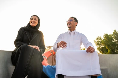 زوج سعودي باللباس التقليدي يضحكان على قارب