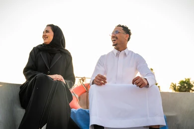 زوجان سعوديان يضحكان على متن قارب وقت الغروب