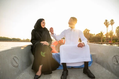 زوجان سعوديان على متن قارب في البحيرة وقت الغروب