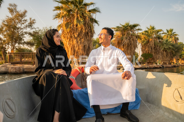 زوجان سعوديان في قارب في البحيرة وقت الغروب