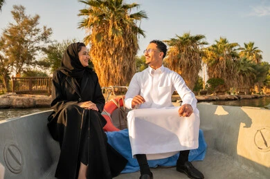 زوجان سعوديان في قارب في البحيرة وقت الغروب