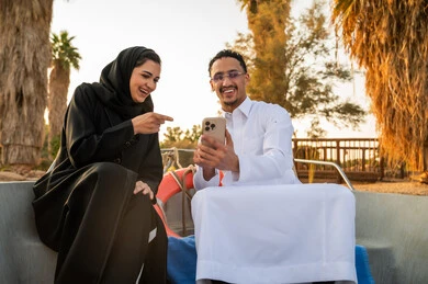 Saudi Couple Laughing with Smartphone on a Boat