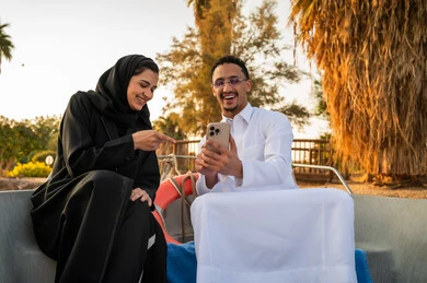 زوجان سعوديان يستخدمان الهاتف الذكي في قارب وقت الغروب