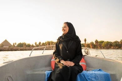 امرأة سعودية على قارب في رحلة نهرية وقت الغروب