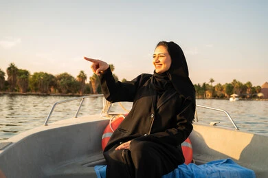 امرأة عربية بالعباءة في قارب وقت الغروب