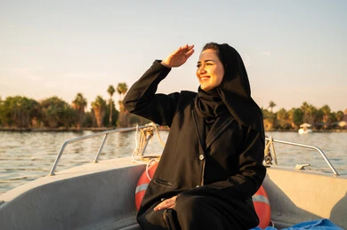 امرأة عربية بالعباية على متن قارب وقت الغروب