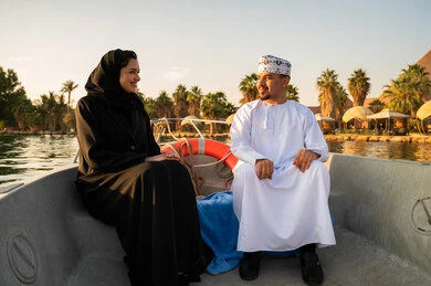 رجل عماني وامرأة بالعباية على متن قارب وقت الغروب